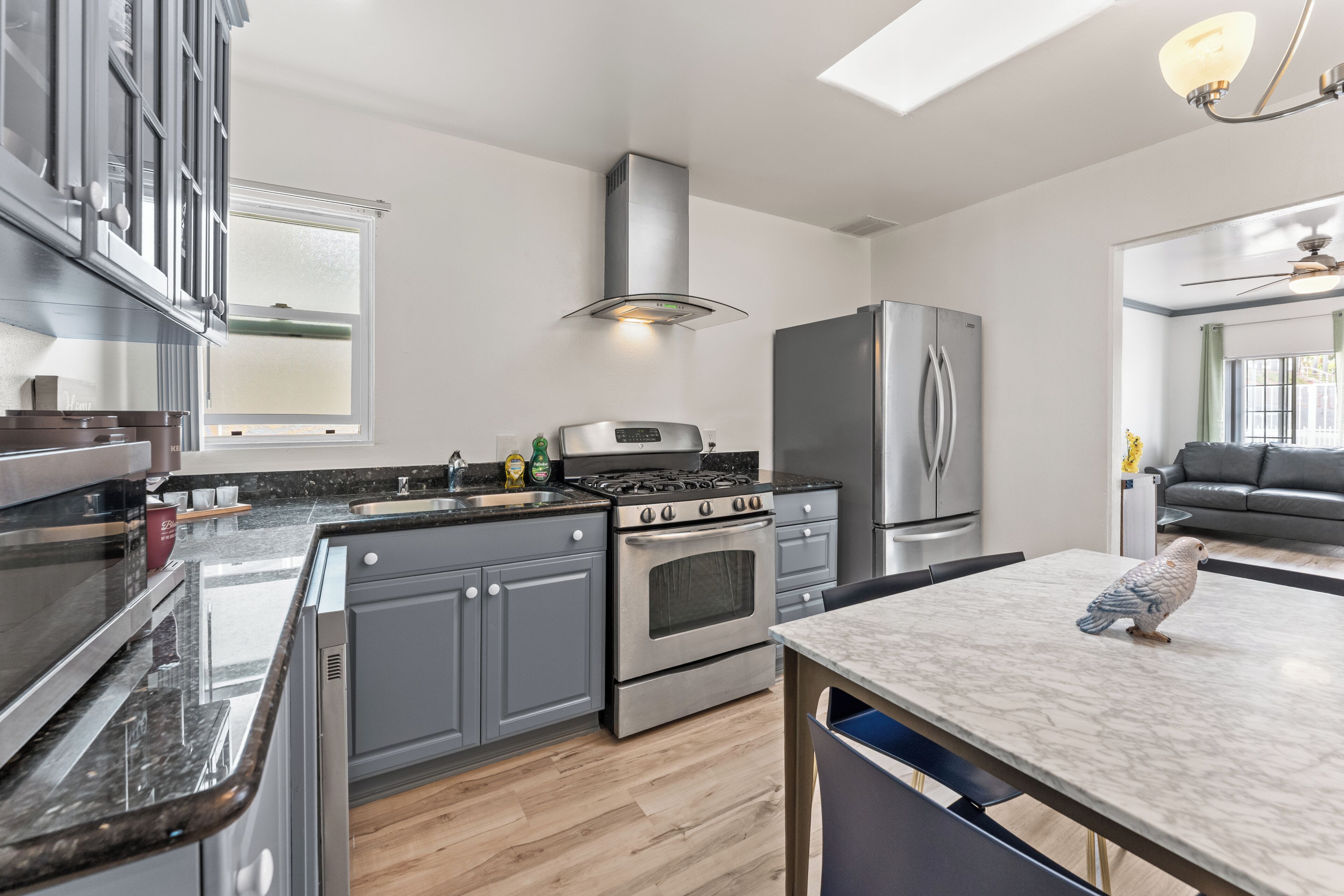 A modern kitchen with stainless steel appliances, a central island, and a dining area.