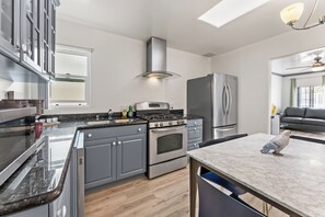 Une cuisine moderne dotée d’appareils électroménagers en acier inoxydable, d’un îlot central et d’un coin repas.
