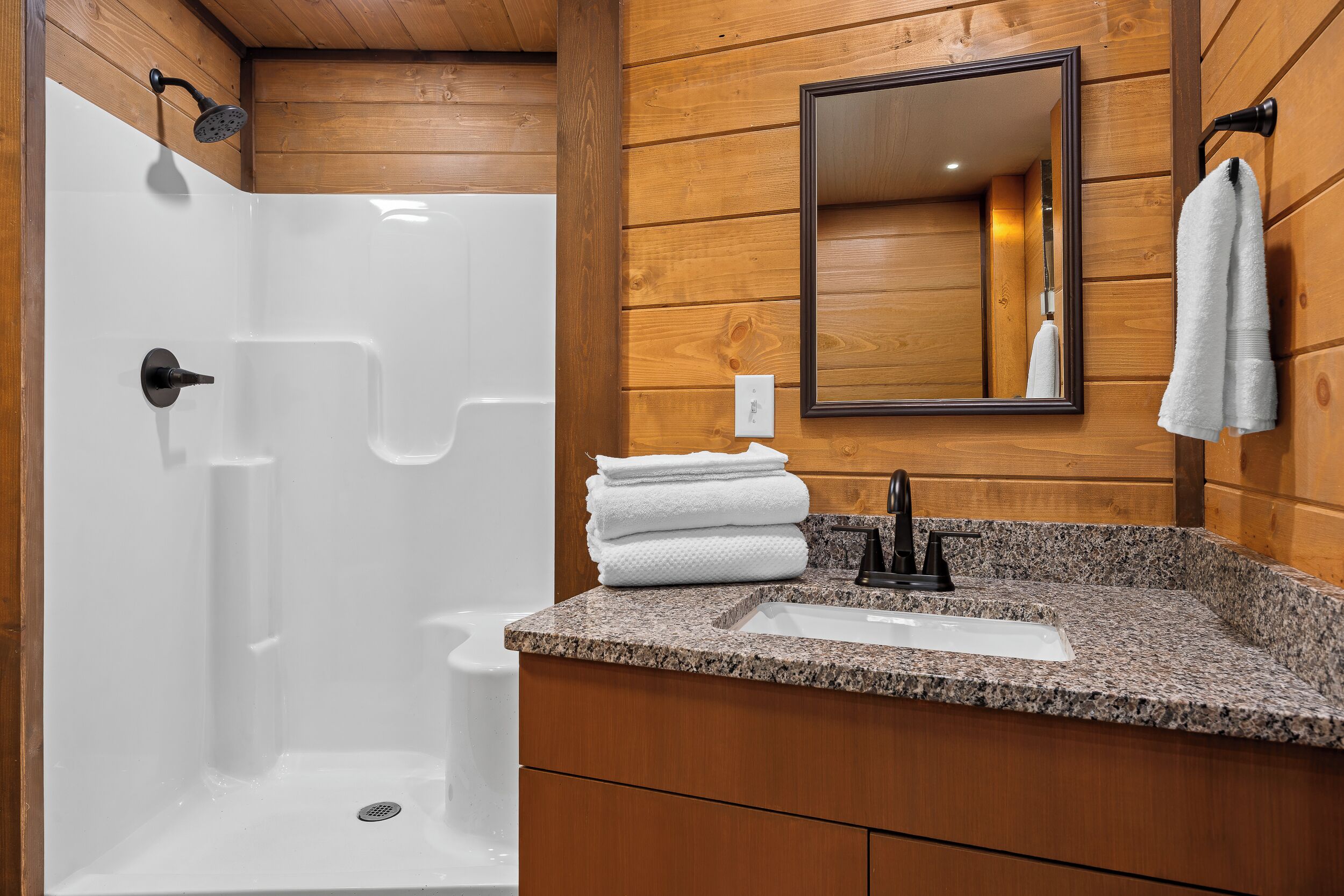 Ein Badezimmer mit Dusche, Waschbecken und Holzverkleidung.