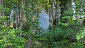 A rustic building surrounded by dense forest. - Honeymoon Suite w/ Exotic Animals + Hot Tub + Zoo (Troutman)