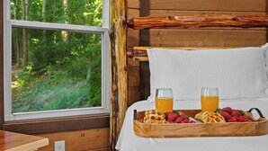 A wooden bed with a white pillow and a tray with waffles and strawberries. - Honeymoon Suite w/ Exotic Animals + Hot Tub + Zoo (Troutman)