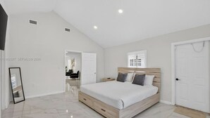 Un dormitorio con una cama, una puerta y una ventana.
