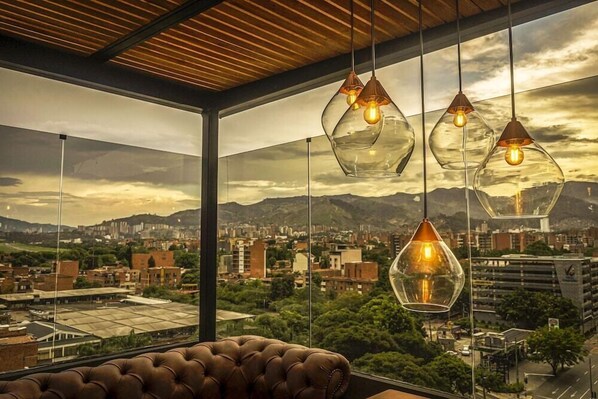 Un interior moderno con ventanas amplias, un sofá de cuero y lámparas colgantes de vidrio.