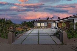 Una casa moderna de dos pisos con entrada pavimentada, garaje y jardín cuidado.
