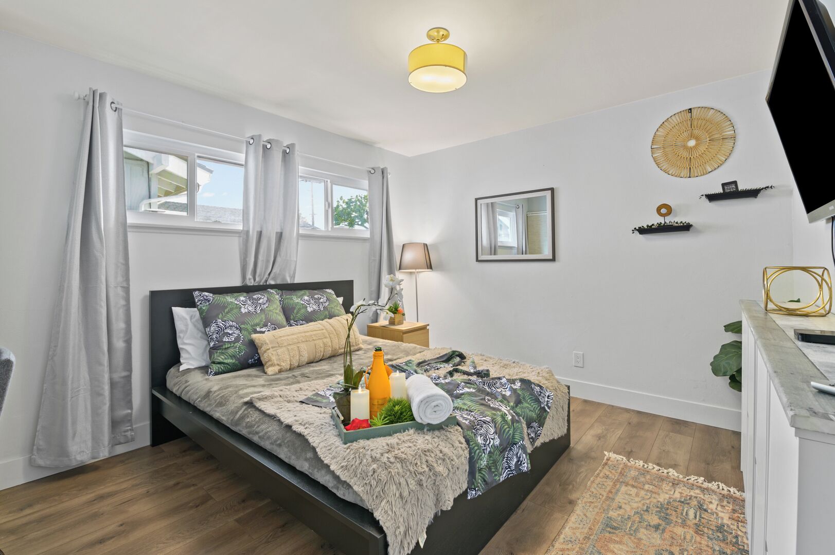 A modern bedroom with a bed, bedside table, lamp, and a TV.