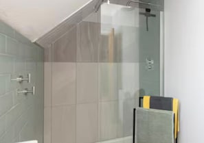 Ein modernes Badezimmer mit einer Duschkabine aus Glas, einem Handtuchhalter und einer sichtbaren Toilette.