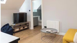 Ett modernt vardagsrum med en TV, ett runt soffbord och en gul soffa.