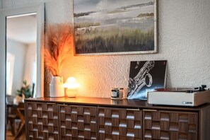 Ein Holzkabinett mit Gittermuster, ein Saxophon-Poster, ein Saxophon, eine Lampe und eine Vase mit Federn.
