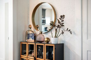 A hallway with a mirror, a cabinet with glassware, and decorative items. - Casa Serena · Historic Spanish Home · SoSo (West Palm Beach)