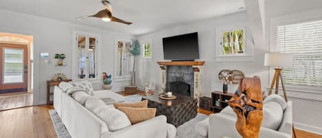 Una sala de estar con chimenea, televisor y ventilador de techo.
