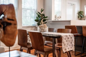 A dining area with a table set for four, surrounded by wooden chairs, and a decorative centerpiece on the table. - Casa Serena · Historic Spanish Home · SoSo (West Palm Beach)