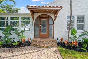 Ein Haus mit einer gefliesten Auffahrt, einer Holz-Pergola und einem Ziegelweg, der zum Eingang führt.