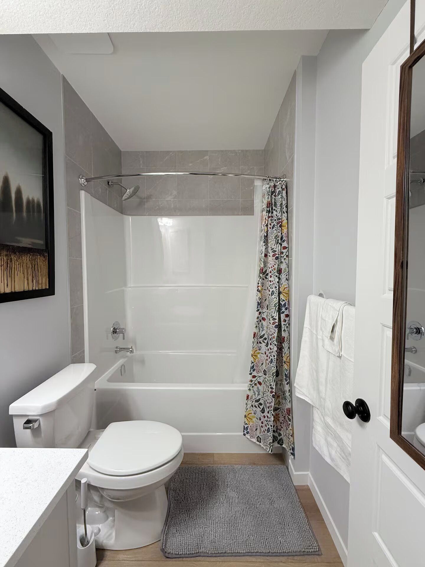 Une salle de bain avec des toilettes, une baignoire, un rideau de douche et un petit tapis.