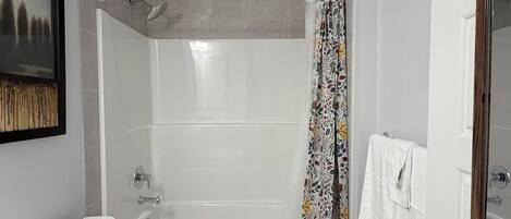 Une salle de bain avec des toilettes, une baignoire, un rideau de douche et un petit tapis.