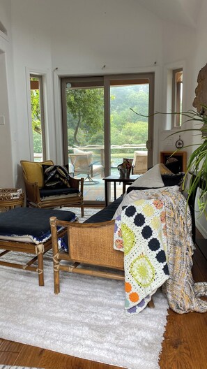 Ein gemütliches Wohnzimmer mit einer Couch, Sesseln, einem Couchtisch und Blick ins Freie.