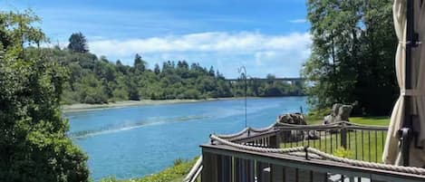 A riverside view with a wooden deck and railing.