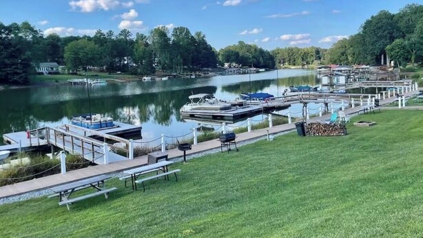 Un parque junto al lago con mesas de picnic, un muelle y botes.