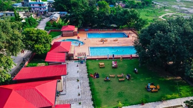 Uma piscina, área de estar ao ar livre e um edifício com telhado vermelho.