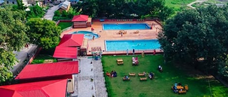 A swimming pool, outdoor seating, and a red-roofed building.