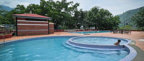 A swimming pool with a tiled edge and a small brick structure nearby.