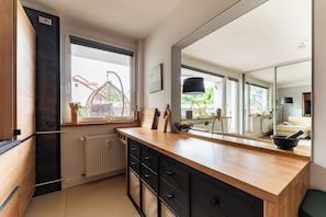Eine moderne Küche mit großem Fenster, einer Holzarbeitsplatte und einer verspiegelten Rückwand.