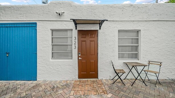 A building with a blue door, a brown door, and a window with shutters. - La Casita Serena | King Bed Near the Beach (West Palm Beach)
