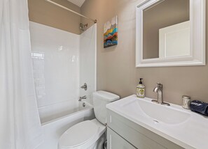 Un bagno con vasca, WC, lavandino e specchio.