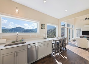 Una cocina moderna con ventanas amplias, lavavajillas y comedor con vista a las montañas.