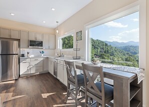 Una cocina moderna con un amplio ventanal que ofrece una vista panorámica de las montañas.