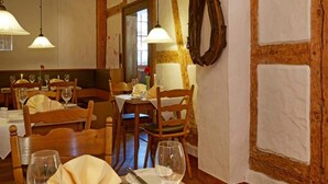 Una zona de dinar amb taules i caires de fusta, llums penjants i un rellotge penjat a la paret.