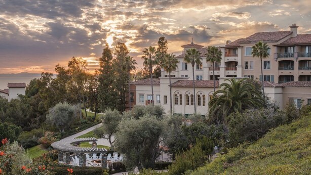 Un resort con diversi edifici, palme e un giardino curato.