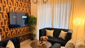 A modern living room with a flat-screen TV, two sofas, a coffee table, and a patterned wall. - Las Americas Apartment 3-bedroom with AC and Heather in Santo Domingo Este. (Santo Domingo Este)