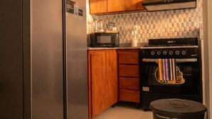 A kitchen with wooden cabinets, a stainless steel refrigerator, a microwave, a stove, and a trash bin. - Las Americas Apartment 3-bedroom with AC and Heather in Santo Domingo Este. (Santo Domingo Este)