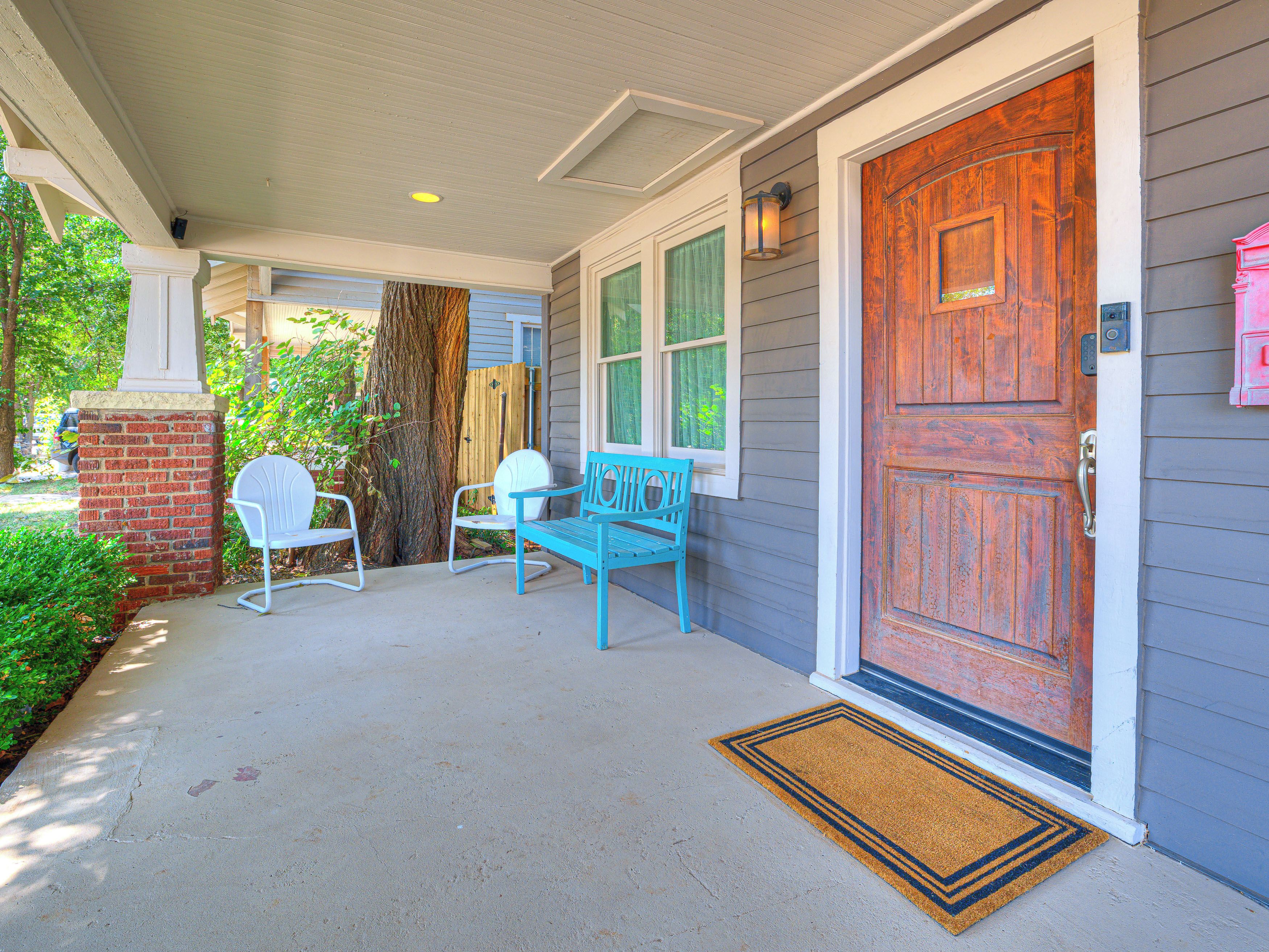 A porch with a wooden door, two chairs, and a bench.