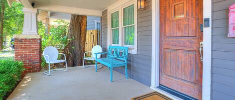 A porch with a wooden door, two chairs, and a bench.