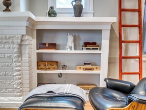 A room with a white brick wall, a white fireplace, and a wooden chest of drawers. - Quiet Luxury Oasis in Uptown OKC (Oklahoma City)