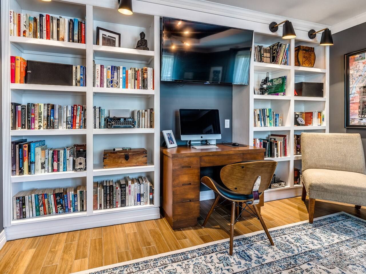 A study room with a wooden desk, a computer, a chair, and bookshelves filled with books.