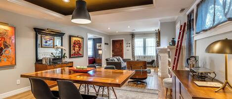 Un comedor amplio con una mesa de madera, sillas y una lámpara colgante.