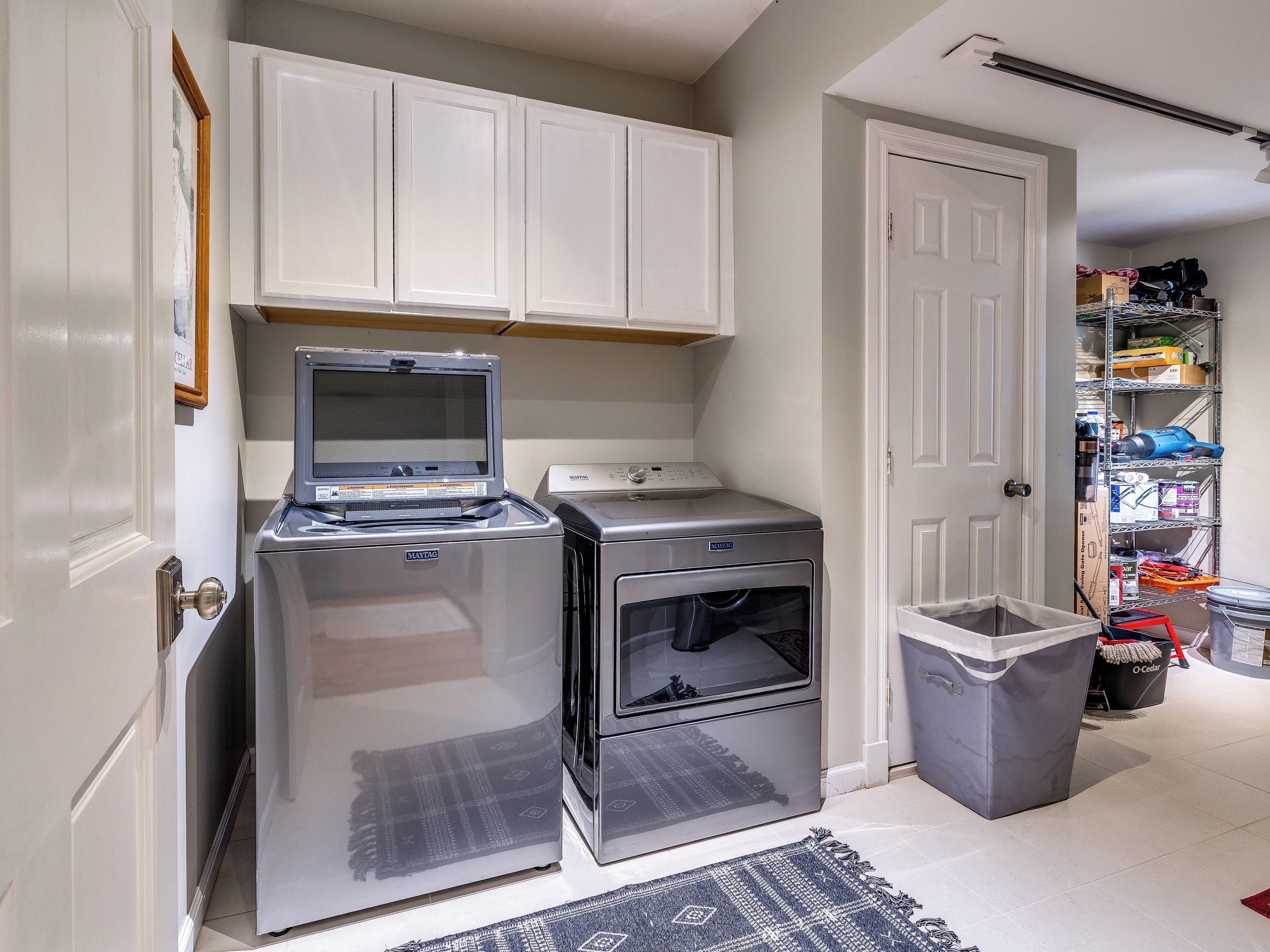 A compact laundry room with a washing machine, dryer, and a small trash bin.