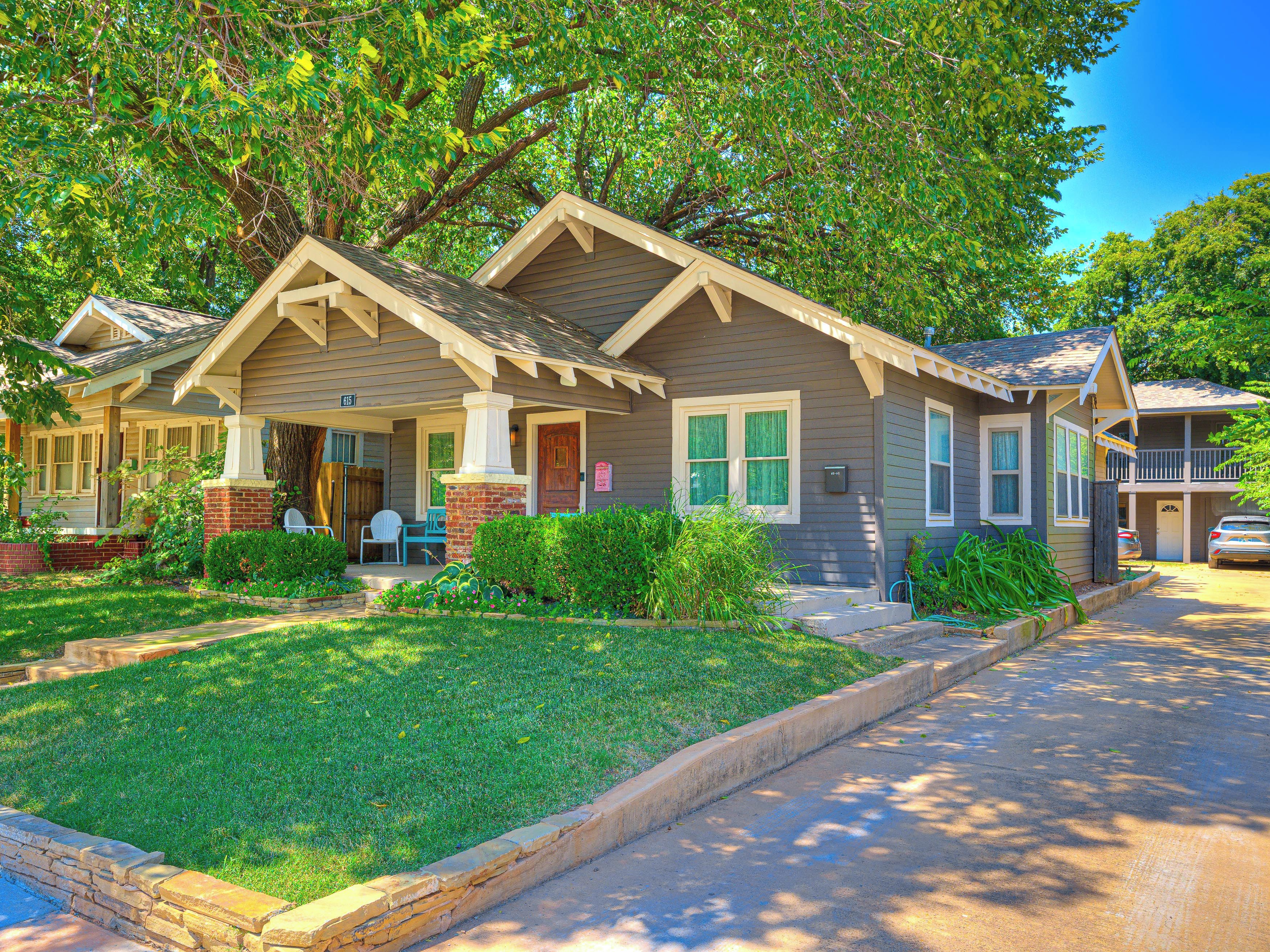 A two-story house with a front porch, a brick chimney, and a well-maintained lawn.