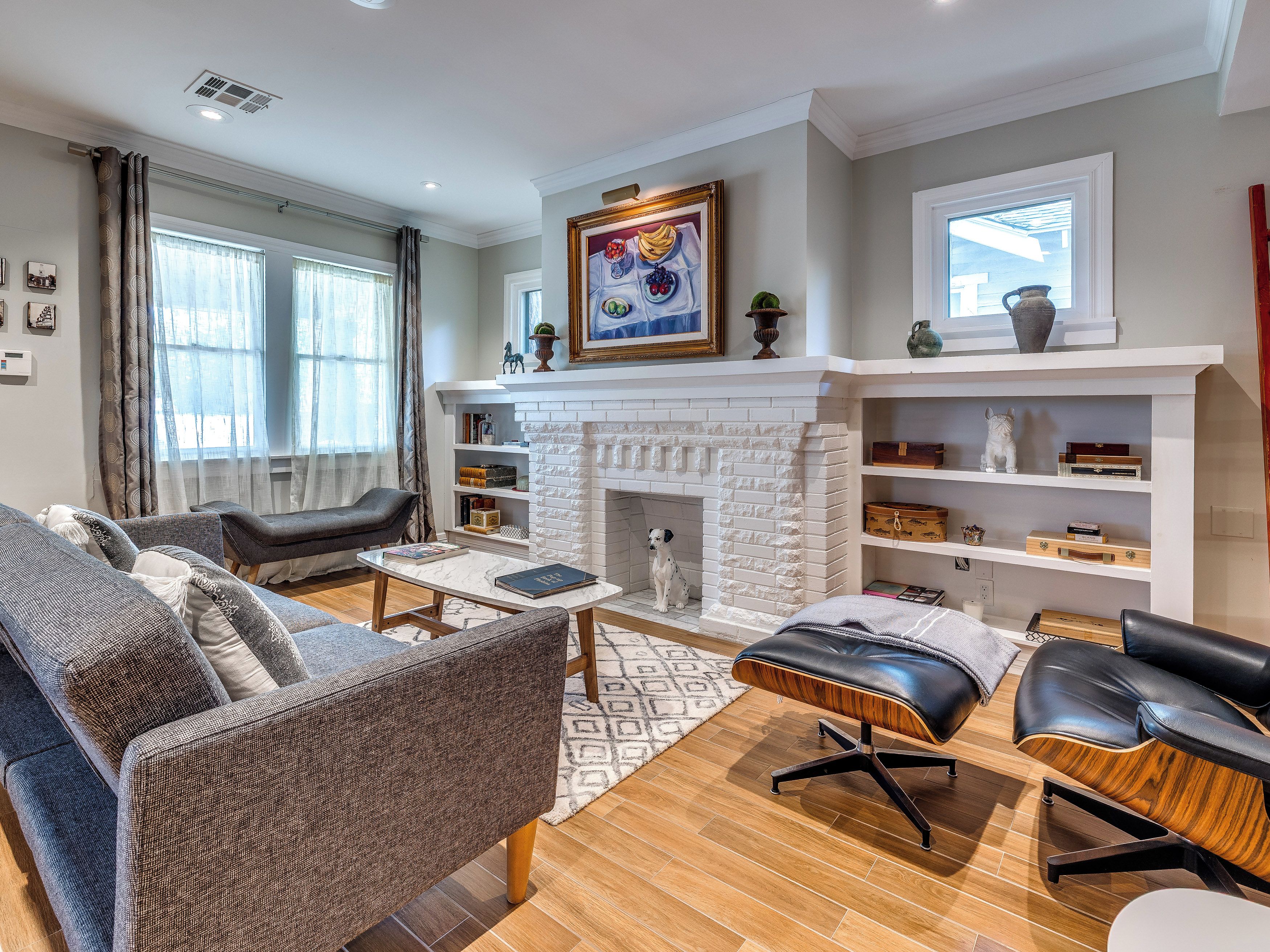 A modern living room with a fireplace, a sofa, a coffee table, and a dog.