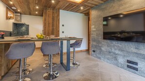 Et moderne køkken med en stenvæg, træloft og en bar med barstole.