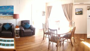 Una sala de estar con un sofá, sillones, una mesa de centro y un comedor con sillas y una mesa.