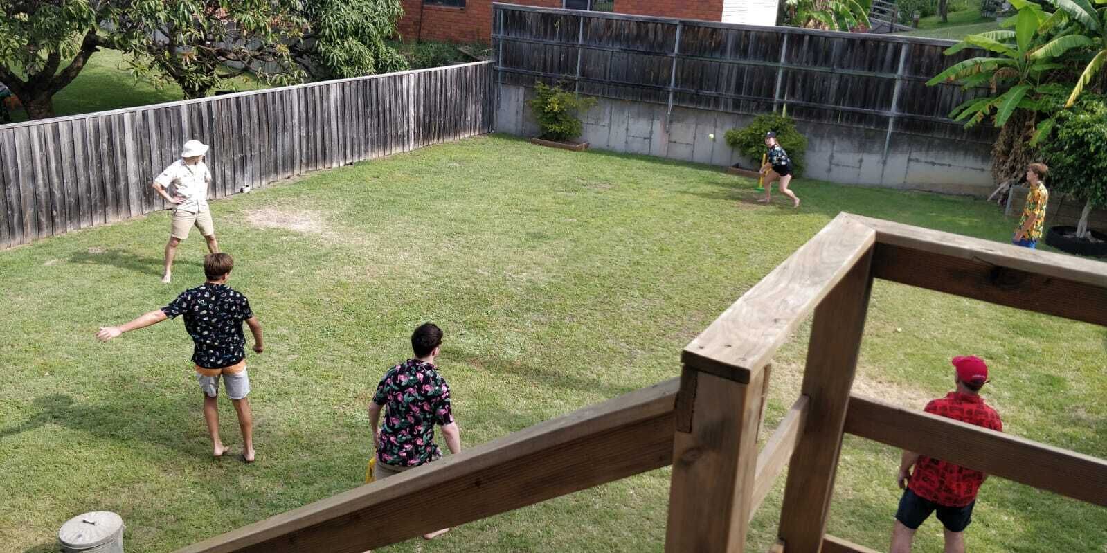 A backyard with a wooden deck, a grassy lawn, and a brick wall.