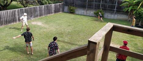 A backyard with a wooden deck, a grassy lawn, and a brick wall.