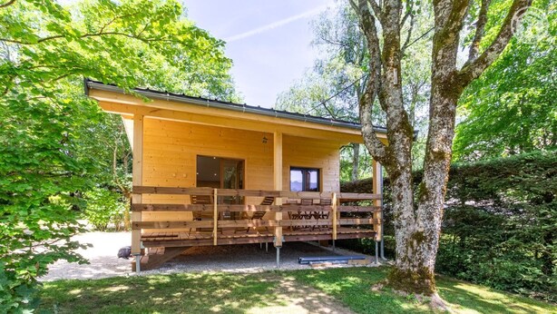 A wooden cabin with a porch, surrounded by trees and greenery. - Chalet du Sud - LE CHATELARD (LE CHATELARD)