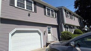 A two-story house with a garage, a driveway, and a parked car.