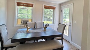 A dining area with a table, chairs, a bench, and a ceiling light fixture.