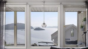 A room with a large window overlooking a body of water, a radiator, and a grey sofa. - 5 Star Holiday Home in Uddevalla (Uddevalla)