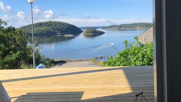 A wooden deck with a view of a lake and forested hills. - 5 Star Holiday Home in Uddevalla (Uddevalla)